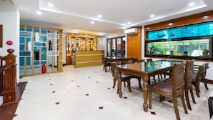 A spacious dining area with a glass-top table and wooden chairs, a reception desk, and a view of a fish tank through large windows. - Sunny Hotel and Apartment (Ho Chi Minh City)
