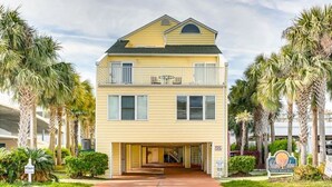 A two-story building with a balcony on the upper floor, a covered entrance, and palm trees surrounding the property. - Quiet 2 bd 2 bath winter/summer getaway, steps to beach. fully furnished. (North myrtal beach)
