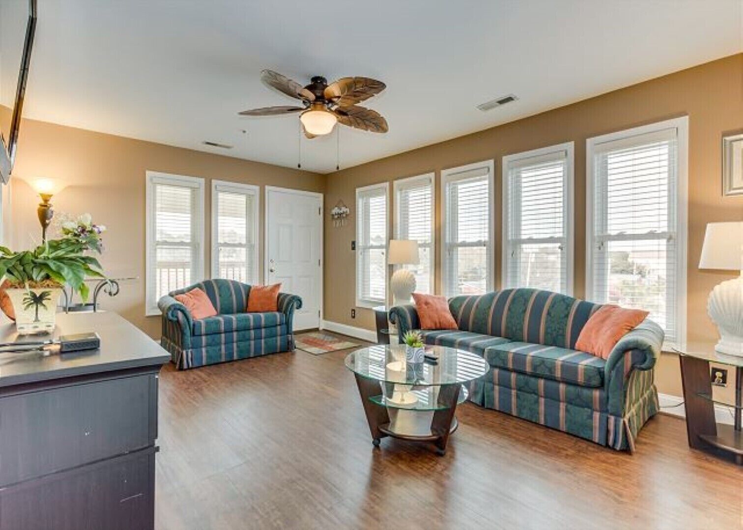 A spacious living room with a large sectional sofa, a coffee table, and a ceiling fan.