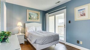 A bedroom with a bed, a nightstand, a lamp, and a potted plant. - Quiet 2 bd 2 bath winter/summer getaway, steps to beach. fully furnished. (North myrtal beach)