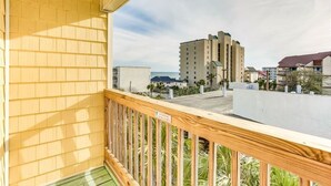 A balcony with a wooden railing overlooking a residential area with buildings and a clear sky. - Quiet 2 bd 2 bath winter/summer getaway, steps to beach. fully furnished. (North myrtal beach)