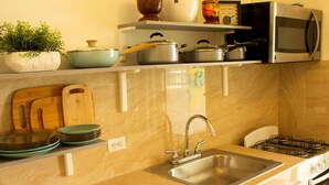 A kitchen with a sink, stove, and various pots and pans on the countertop.