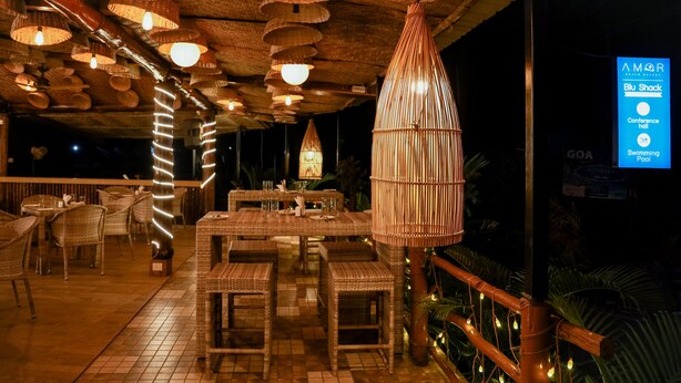 Un espace extérieur aménagé pour les repas, avec des meubles en osier et des luminaires suspendus.