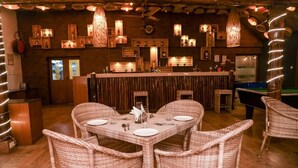 Un restaurant doté de mobilier en osier, d’un bar et d’une décoration en bois.