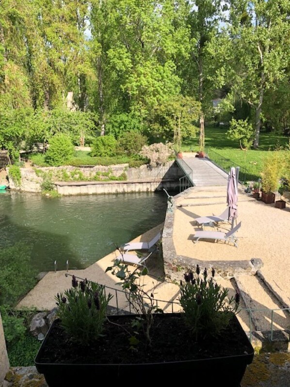 A serene outdoor area with a pond, lounge chairs, and potted plants.