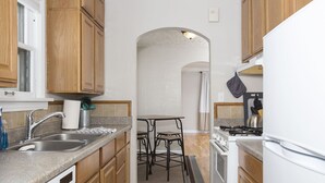 A compact kitchen with wooden cabinets, a built-in dishwasher, a gas stove, and a small dining area with two stools. - Triangular Casa in Billings (Billings)