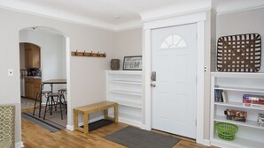 A home interior with a wooden floor, a bench, a door, a bench with a mat, a wall-mounted shelf, and a basket. - Triangular Casa in Billings (Billings)