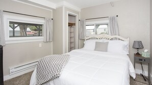 A bedroom with a bed, a bedside table with a lamp, a heater, and a window with curtains. - Triangular Casa in Billings (Billings)