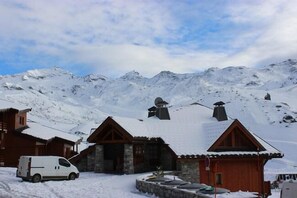 A snow-covered mountain village with wooden buildings and a white van parked in front. - 100m from ski slopes, 3rd floor, sauna, hammam, balcony, tv, 53m², Val Thorens (Val Thorens)