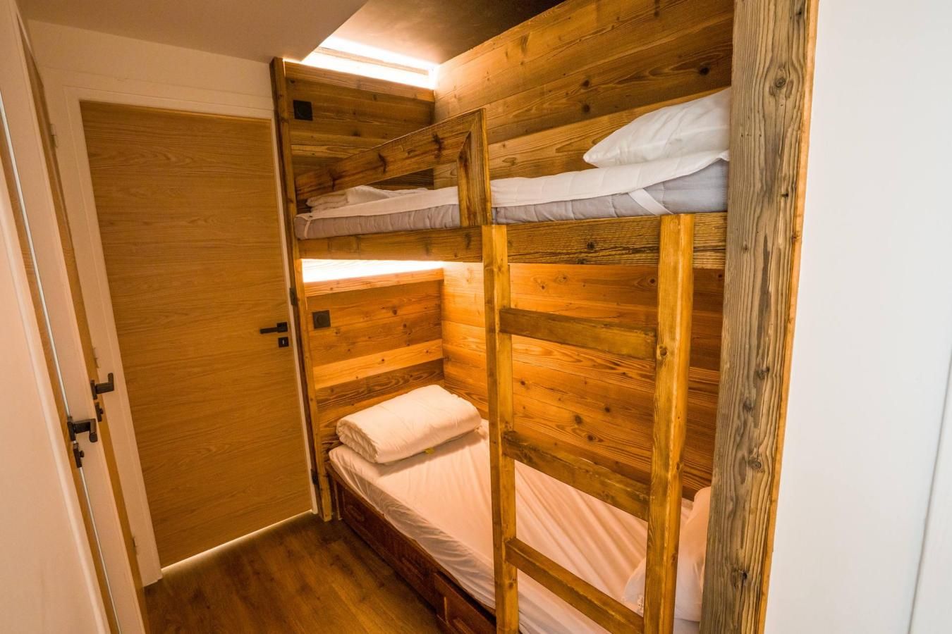 A wooden bunk bed room with a door and a small window.