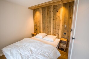 A bedroom with a wooden headboard, two bedside tables, and a bed with white bedding.