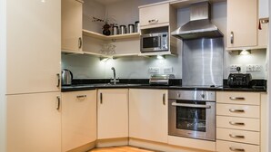 Une cuisine moderne dotée d’appareils électroménagers en acier inoxydable, de meubles blancs et d’un plancher en bois.