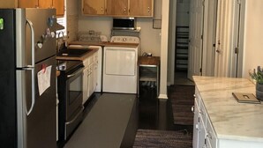 Une cuisine avec des meubles en bois, un réfrigérateur, une cuisinière, un four à micro-ondes et un lave-linge.