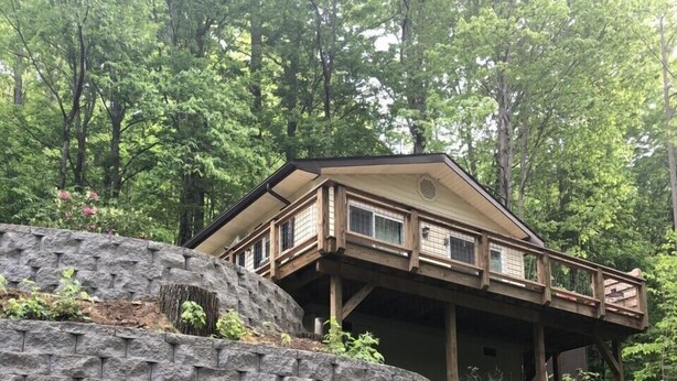 Une cabane dotée d’un mur de soutènement en pierre et d’une terrasse en bois.