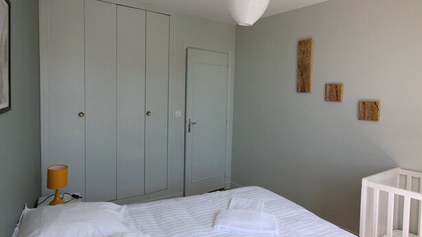 Ein Schlafzimmer mit einem Bett, einem Babybett und einem Kleiderschrank.