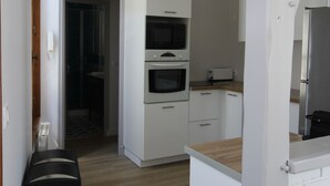 Eine moderne Küche mit weißen Schränken, einem Edelstahlkühlschrank und einer Mikrowelle.