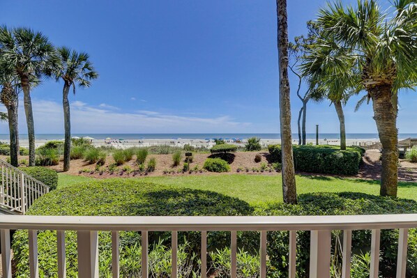 A beachfront property with a view of the ocean, palm trees, and a well-maintained garden.