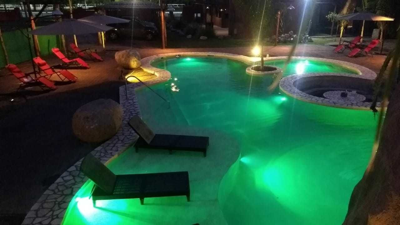 Una piscina de diseño curvo, rodeada de sillones de descanso y un camino de piedra.