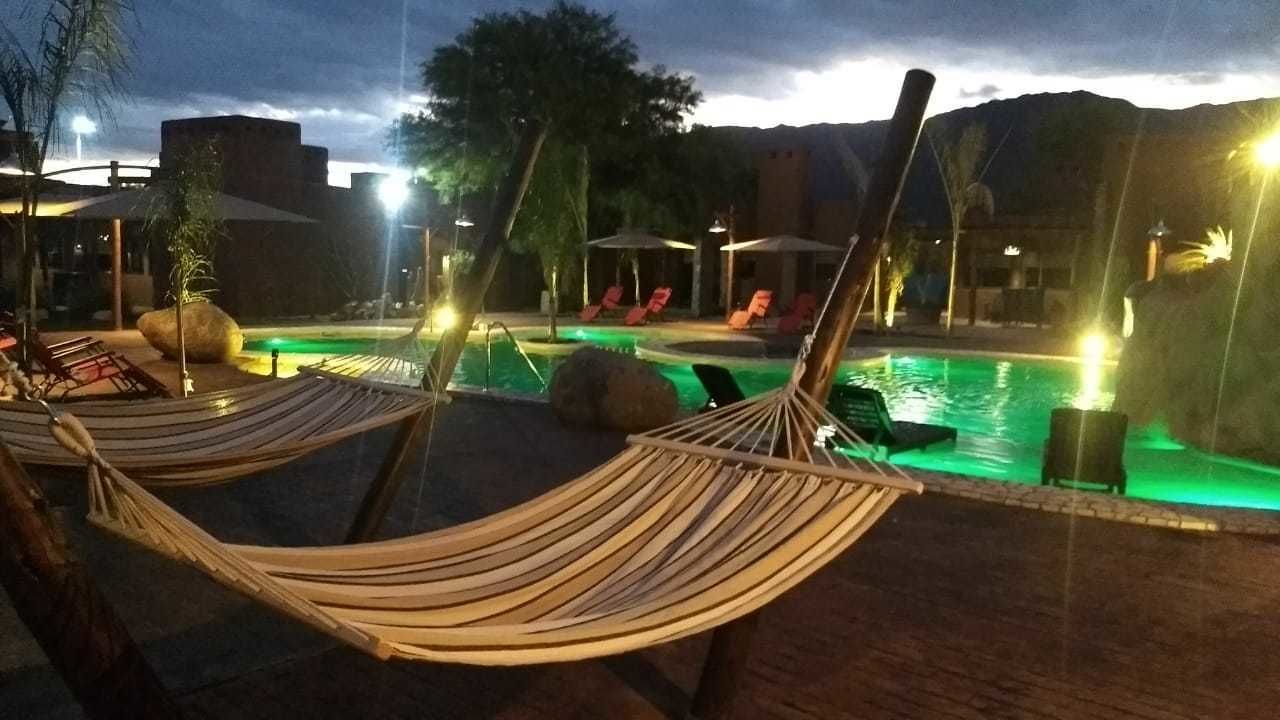 A poolside area with two hammocks, lounge chairs, and a pool.