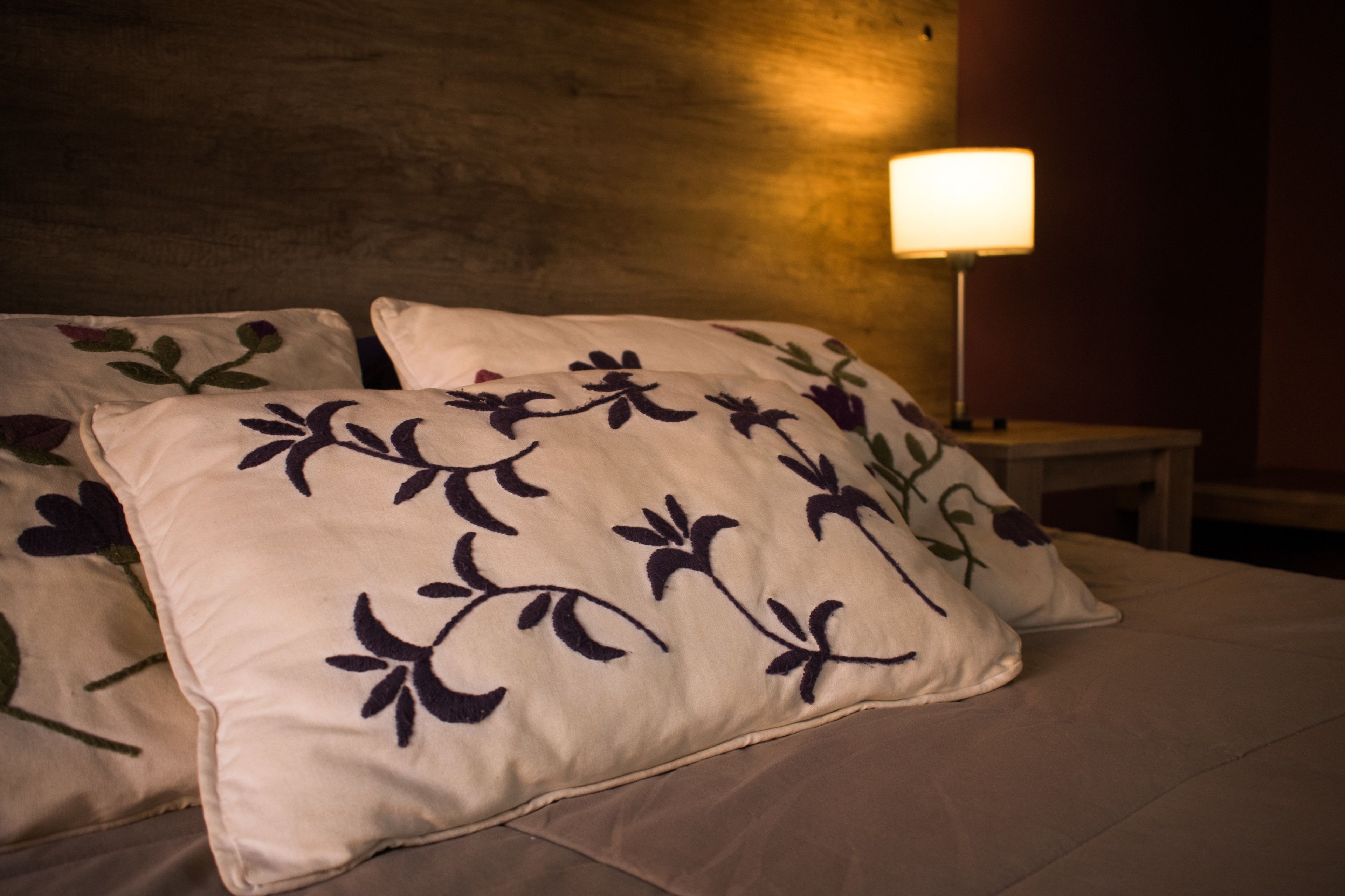 Un lit avec des oreillers à motifs floraux et une lampe de chevet.