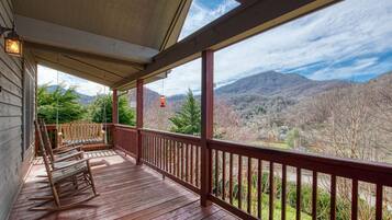 A wooden deck with a railing overlooking a mountainous landscape.