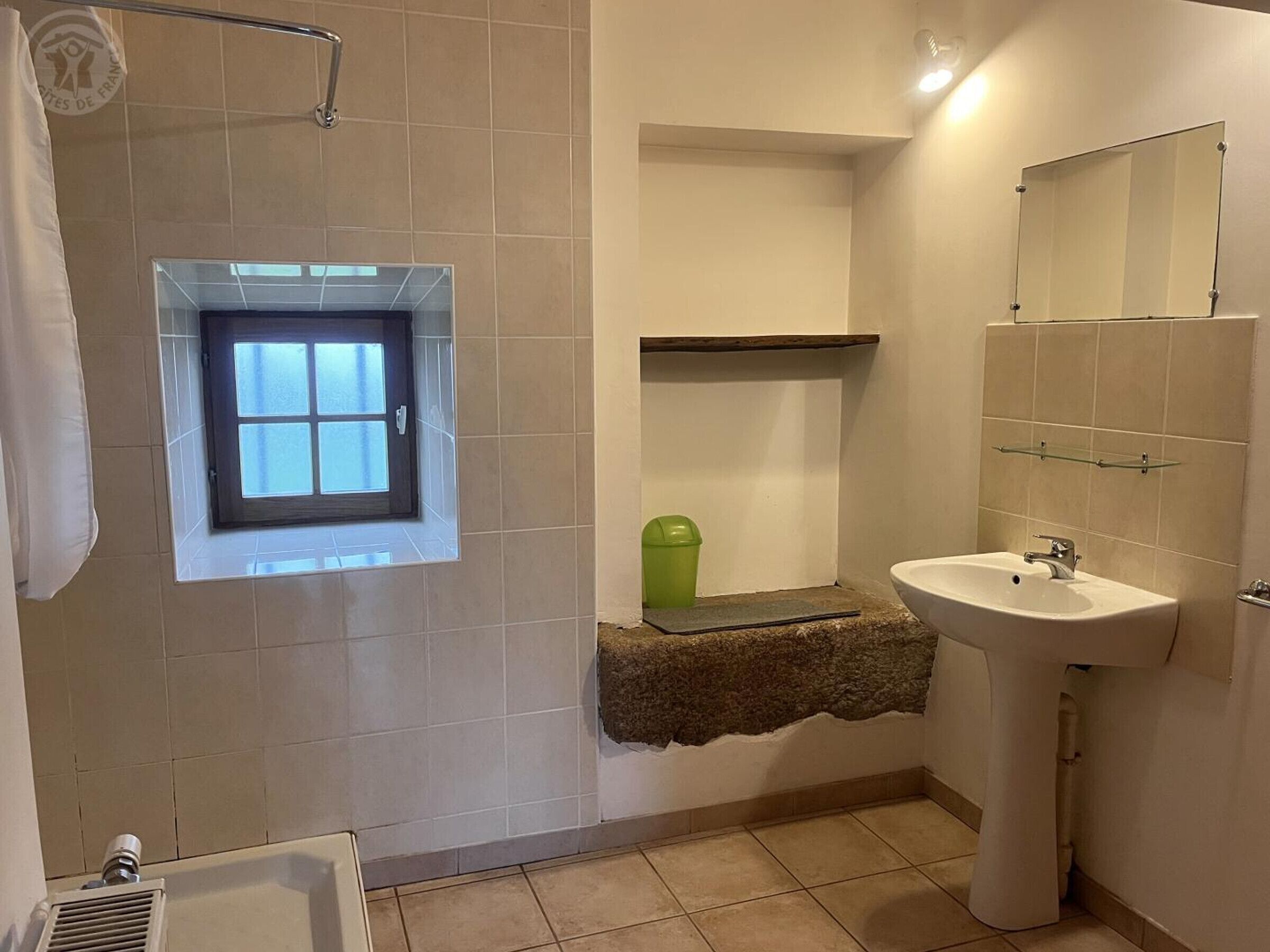 A bathroom with a window, a sink, and a shower.