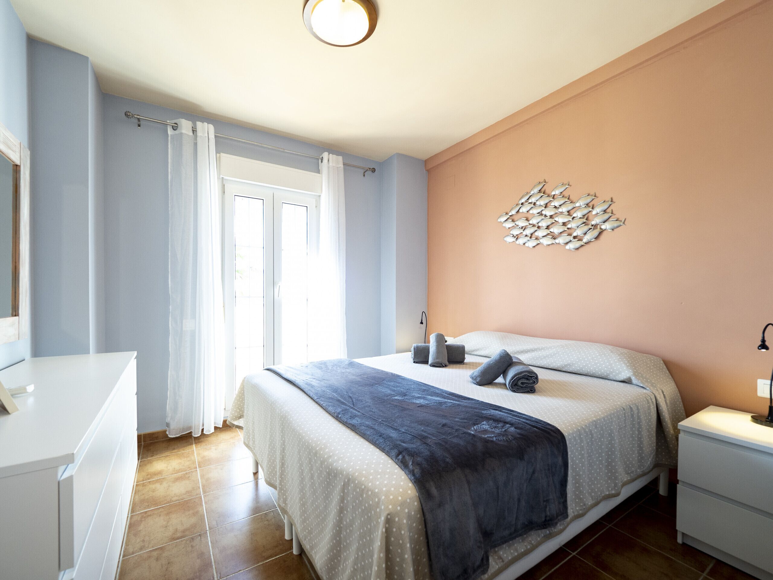 A bedroom with a bed, a nightstand, a dresser, and a wall art piece.