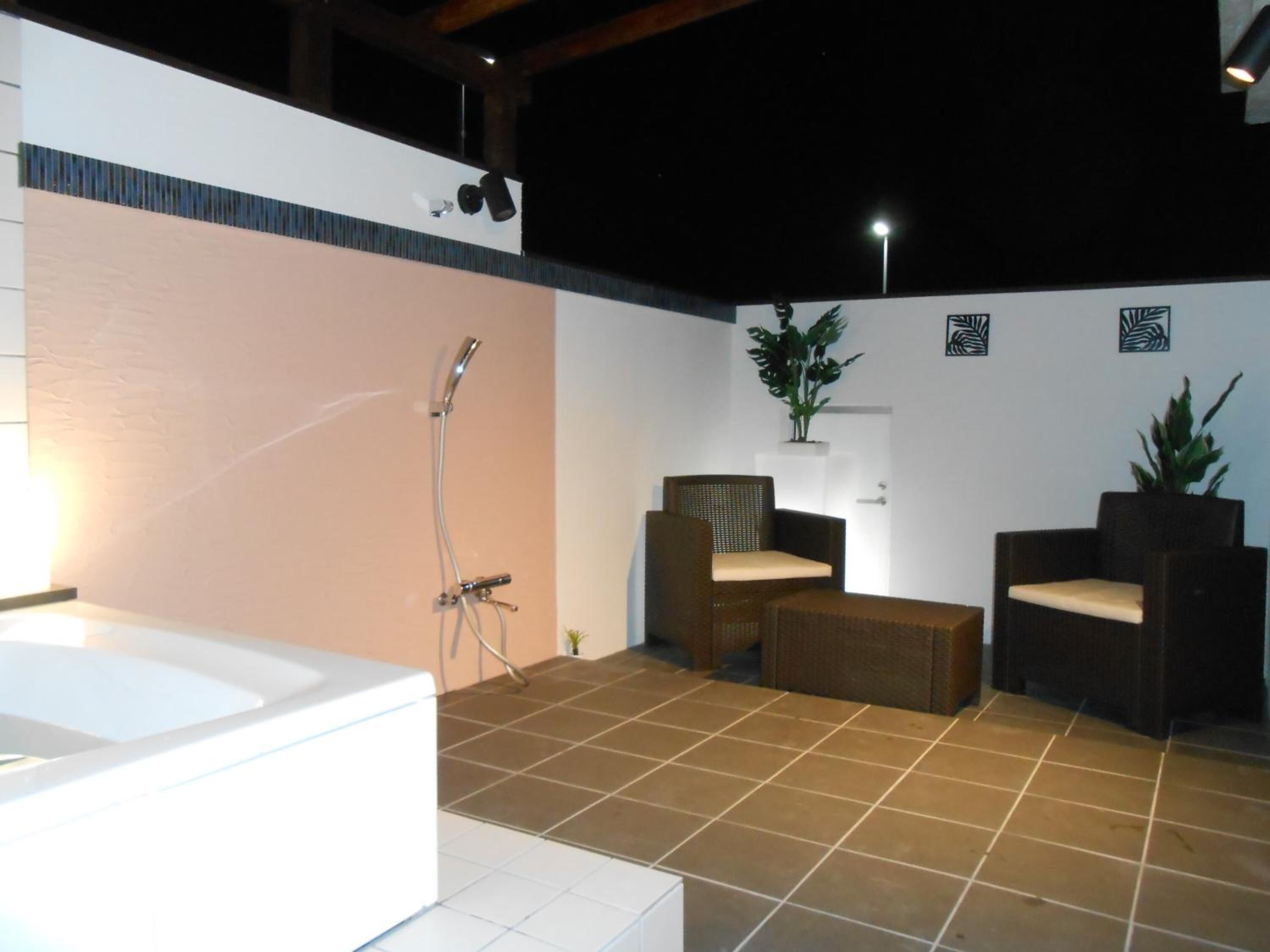 A bathroom with a bathtub, a shower, and two wicker chairs.