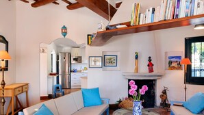Un salon chaleureux avec un canapé, une table ronde en verre, une cheminée et une bibliothèque remplie de livres.
