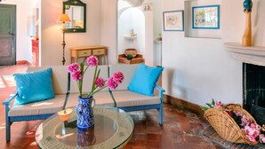 Un salon chaleureux avec une table basse en verre, un canapé orné de coussins bleus et une cheminée.