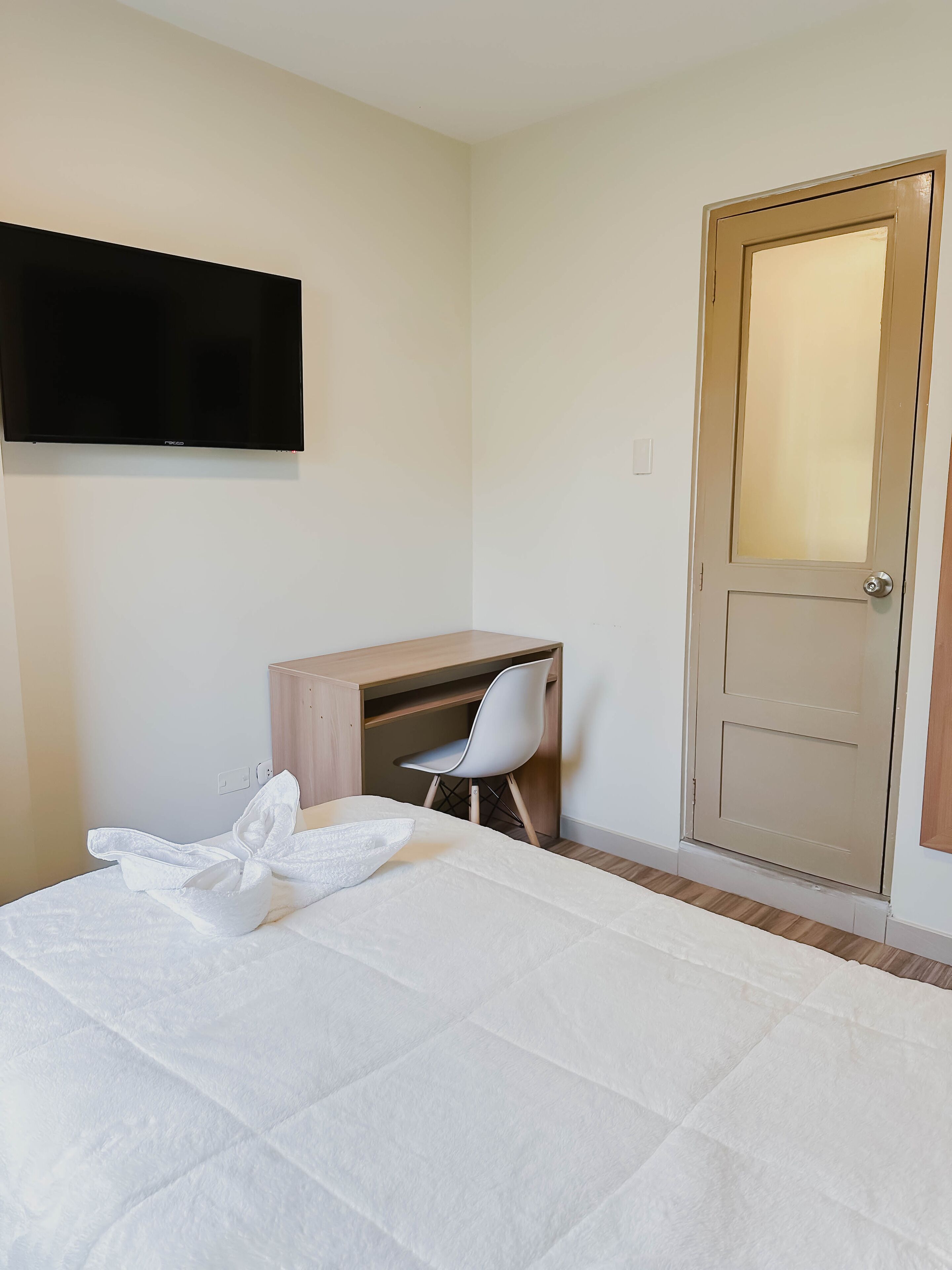 Una habitación de hotel con cama, escritorio, silla y puerta.
