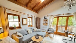 A cozy living room with a grey sectional sofa, a wooden coffee table, and a dining area with a table and chairs. - Chalet Belle Kitz 1 by belle-stay (Kitzbühel)