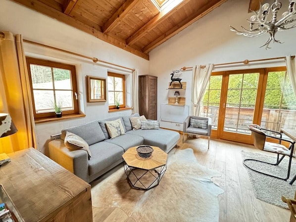 A cozy living room with a grey sectional sofa, a wooden coffee table, and a dining area with a table and chairs.