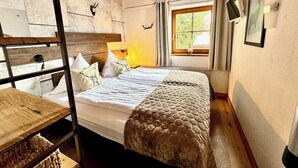 A room with a bunk bed, a wooden desk, a window with curtains, and a wall-mounted picture. - Chalet Belle Kitz 1 by belle-stay (Kitzbühel)