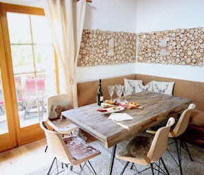 A dining area with a wooden table, chairs, a sofa, and a decorative wall piece.