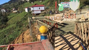 A wooden deck with a metal railing, a yellow bollard, and a sign with text. - Sapa Dao Homestay (Sa Pa)
