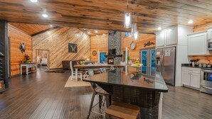 Una cucina moderna con isola centrale, pareti in legno e camino in pietra.