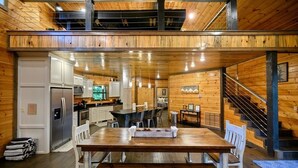 Un'ampia cucina con elettrodomestici moderni, una zona pranzo con tavolo e sedie in legno e una scala che conduce a un livello superiore.