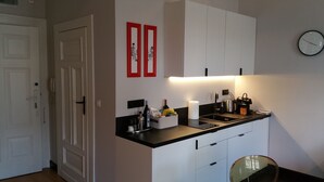Une cuisine moderne avec des meubles blancs, un plan de travail noir et une horloge murale.