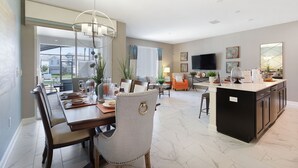 A spacious living area with a dining table, chairs, and a kitchen island. - ☀ Champions Gate -5★ Clubhouse - Water Slides & Lazy River - Tiki Bar & Grill ✈ (Champions Gate)