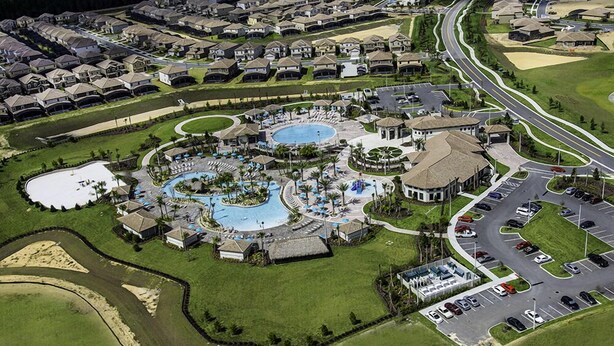 An aerial view of a resort with multiple swimming pools, a central plaza, and a parking area. - ☀ Champions Gate -5★ Clubhouse - Water Slides & Lazy River - Tiki Bar & Grill ✈ (Champions Gate)