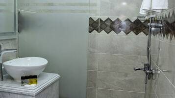 A bathroom with a glass-enclosed shower, a white sink, and a toilet.