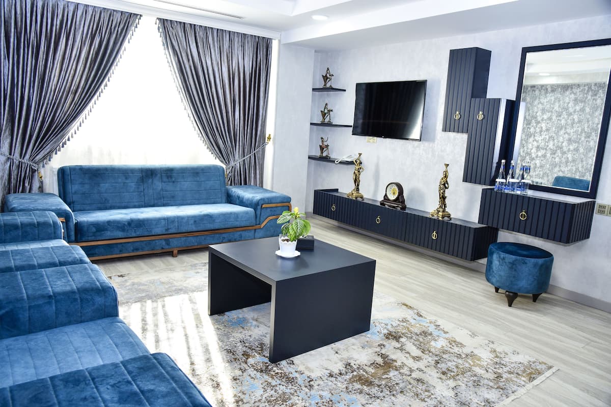 Un salon moderne avec un canapé bleu, une table basse noire et un téléviseur fixé au mur.