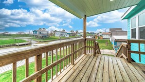 A wooden deck with a view of a river and houses in the background.