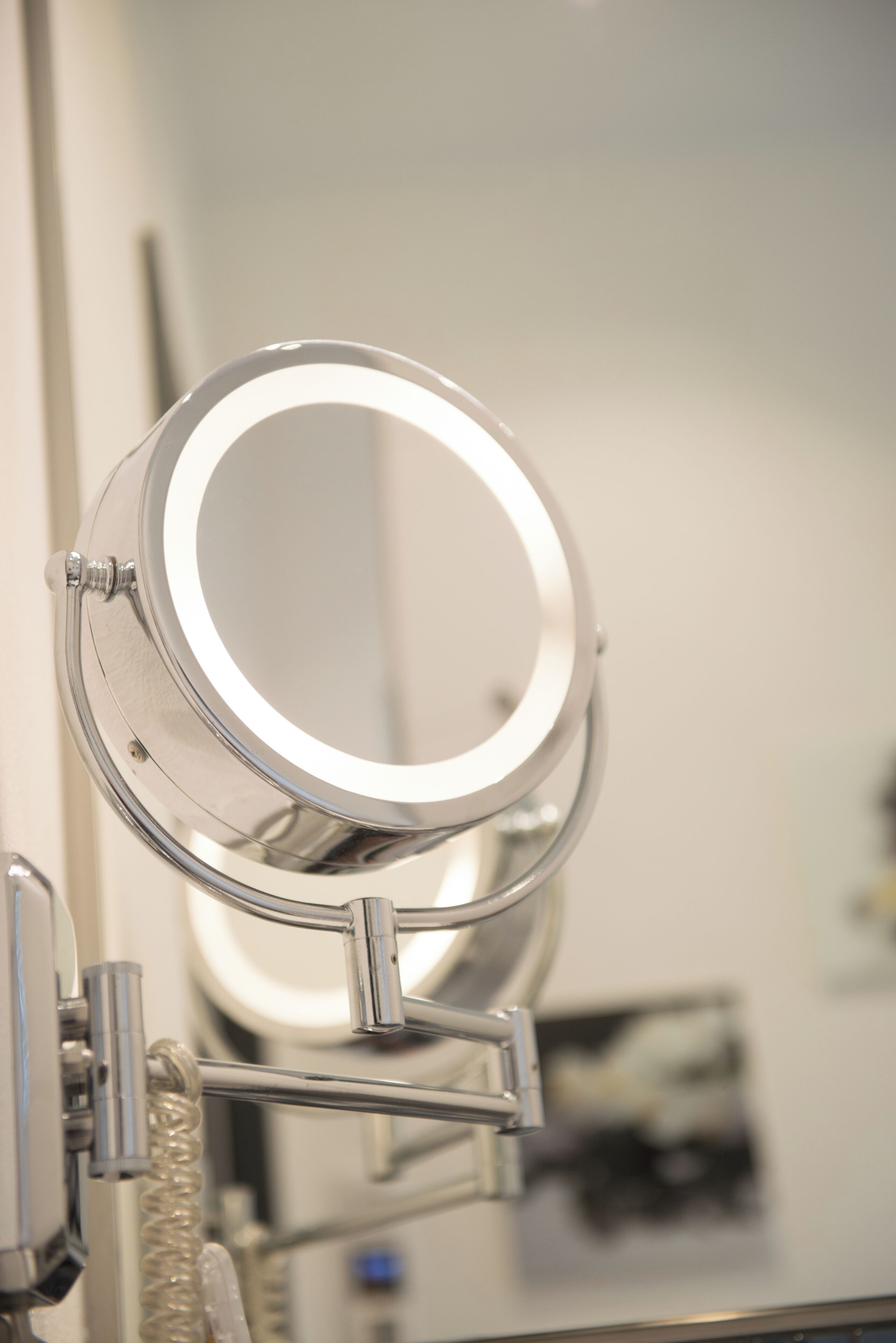 A bathroom vanity with a round mirror and a light.