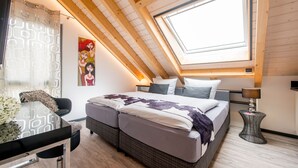 A bedroom with a skylight, a bed with a purple and white bedspread, a small table with a lamp, and a chair. - "Silber-Mops" 5***** Designer Apartment for Connoisseurs ♥ Garden Access ♥ Parking Space (Bensheim)