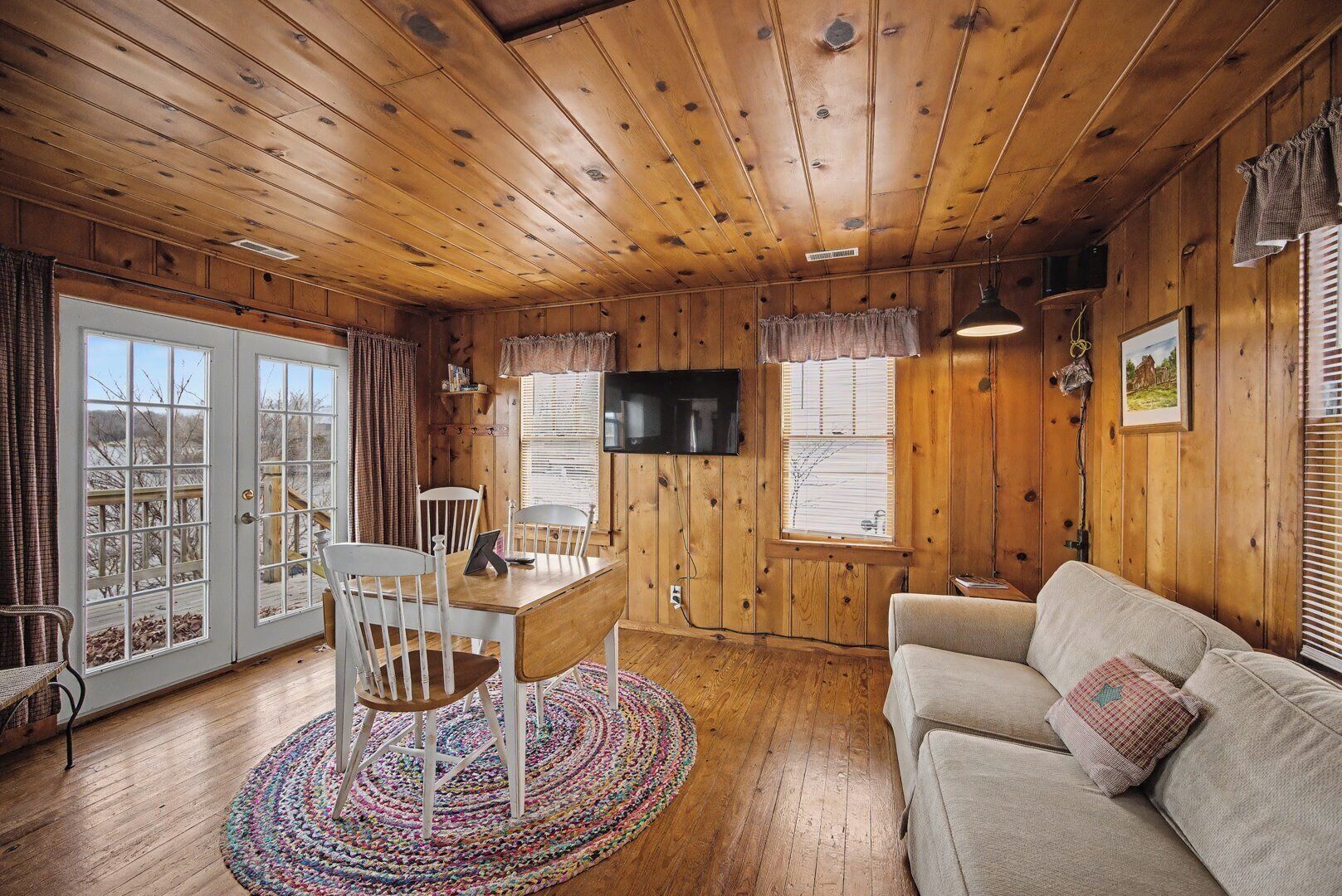 Un intérieur en bois comprenant une table à manger, des chaises, un canapé et un téléviseur.