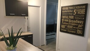 Eine moderne Küche mit einem Esstisch, einem Topf mit Pflanze und einem an der Wand befestigten Schild, das nahegelegene Orte auflistet.