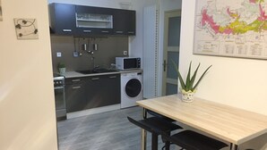 Eine moderne Küche mit Edelstahlgeräten, ein Essbereich mit einem Holztisch und schwarzen Stühlen sowie eine Karte an der Wand.