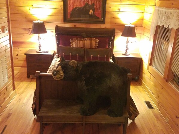 A wooden cabin room with a bed, two nightstands, a lamp, and a framed picture on the wall. - MOUNTAIN JOY COTTAGES #10- BIG BEAR (Maggie Valley)